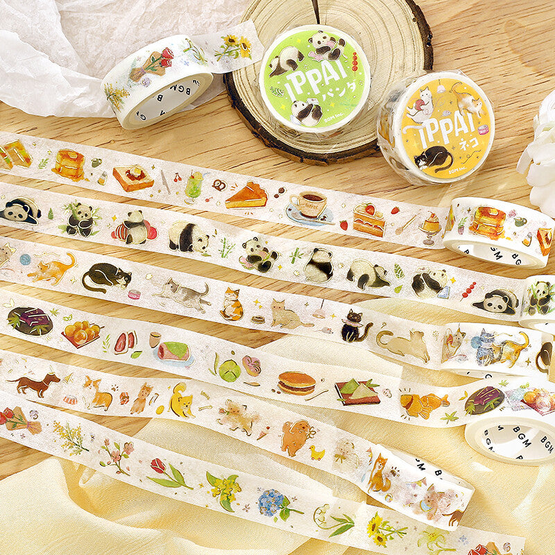 Set of decorative tape rolls with animal and food illustrations on a wooden surface.
