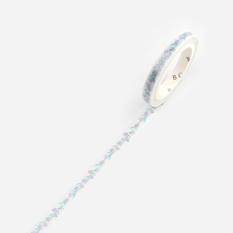 A roll of washi tape with a delicate pastel floral pattern in lavender, mint green, and light blue on a white background, shown diagonally with the tape unrolled.
