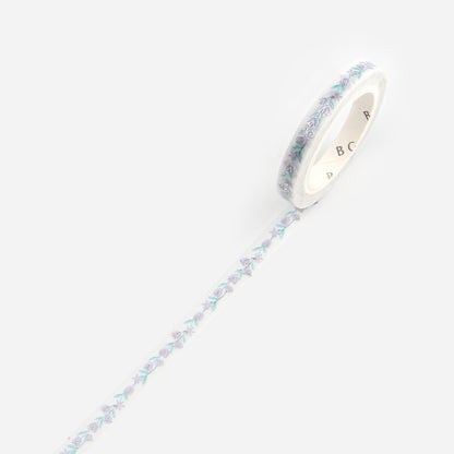 A roll of washi tape with a delicate pastel floral pattern in lavender, mint green, and light blue on a white background, shown diagonally with the tape unrolled.