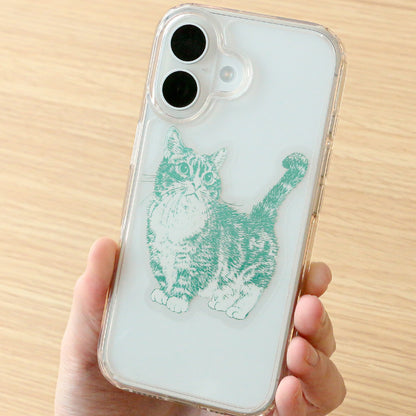 A hand holding a clear phone case with a green cat sticker, shown against a light wood background.