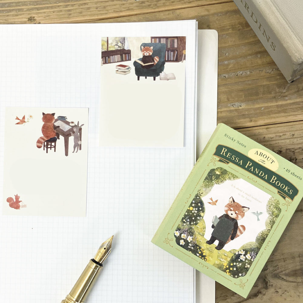 Notebook with cute illustrations, a pen, and a book titled 'Ressa Panda Books' on a wooden surface.