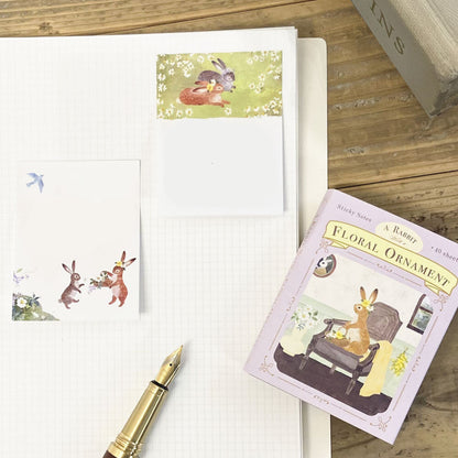 Notebook with decorative sticky notes featuring rabbits on a wooden surface