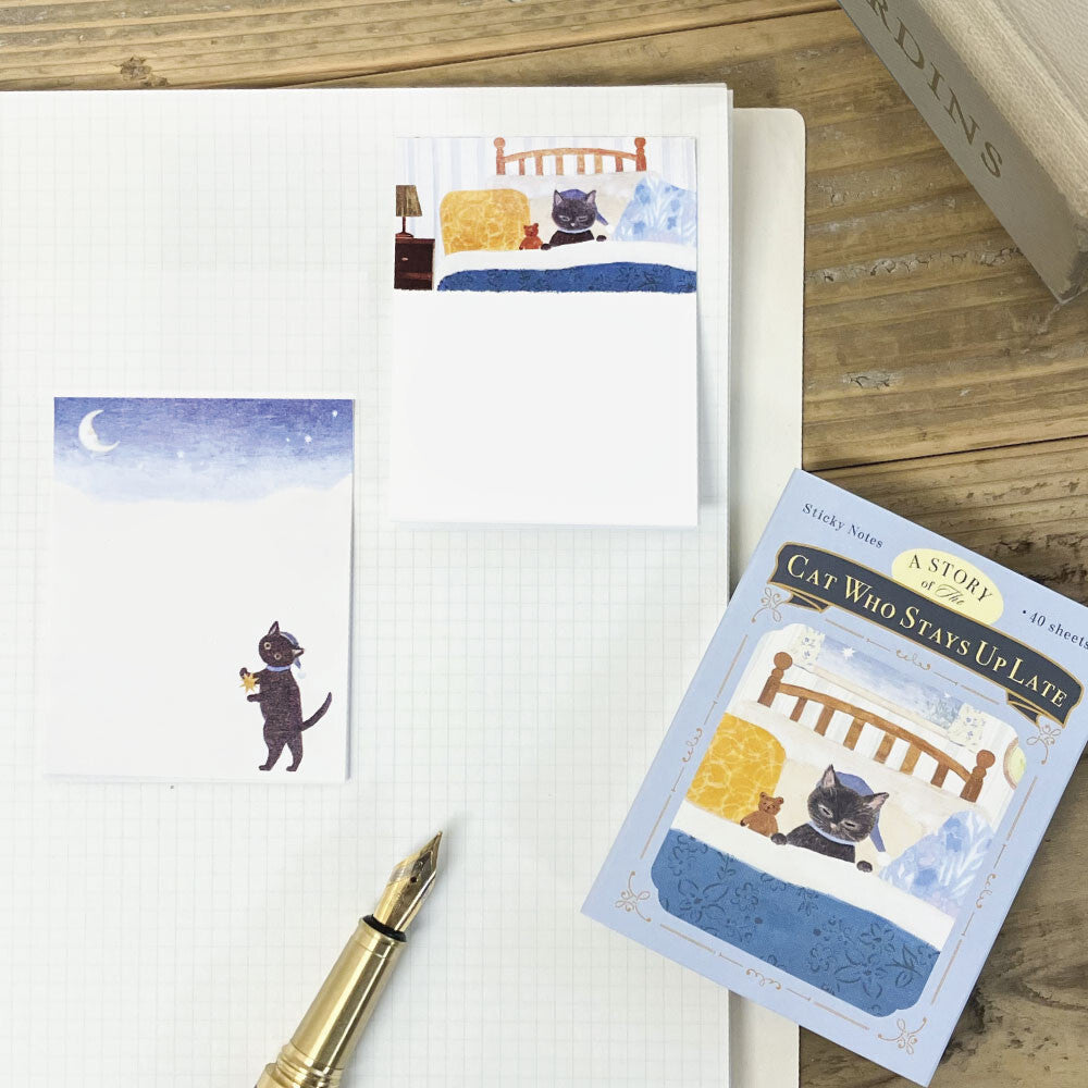 Notebook with cat-themed sticky notes and a pen on a wooden surface