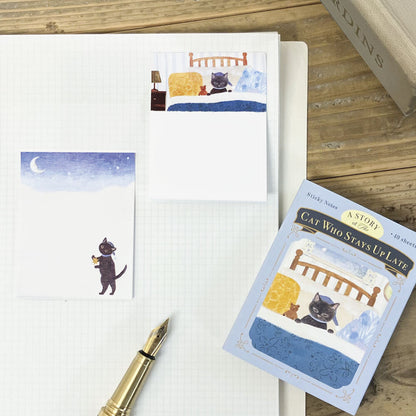 Notebook with cat-themed sticky notes and a pen on a wooden surface