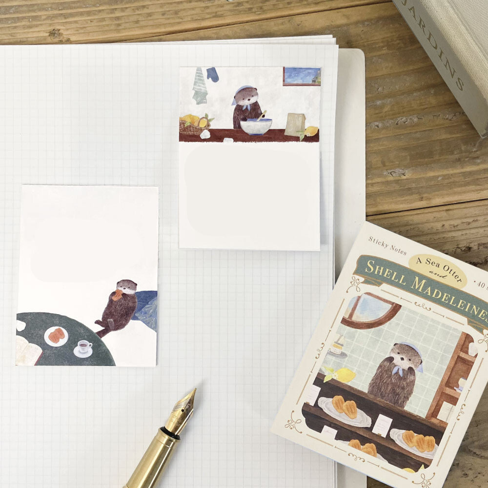Notebook with stationery items featuring otters on a wooden surface