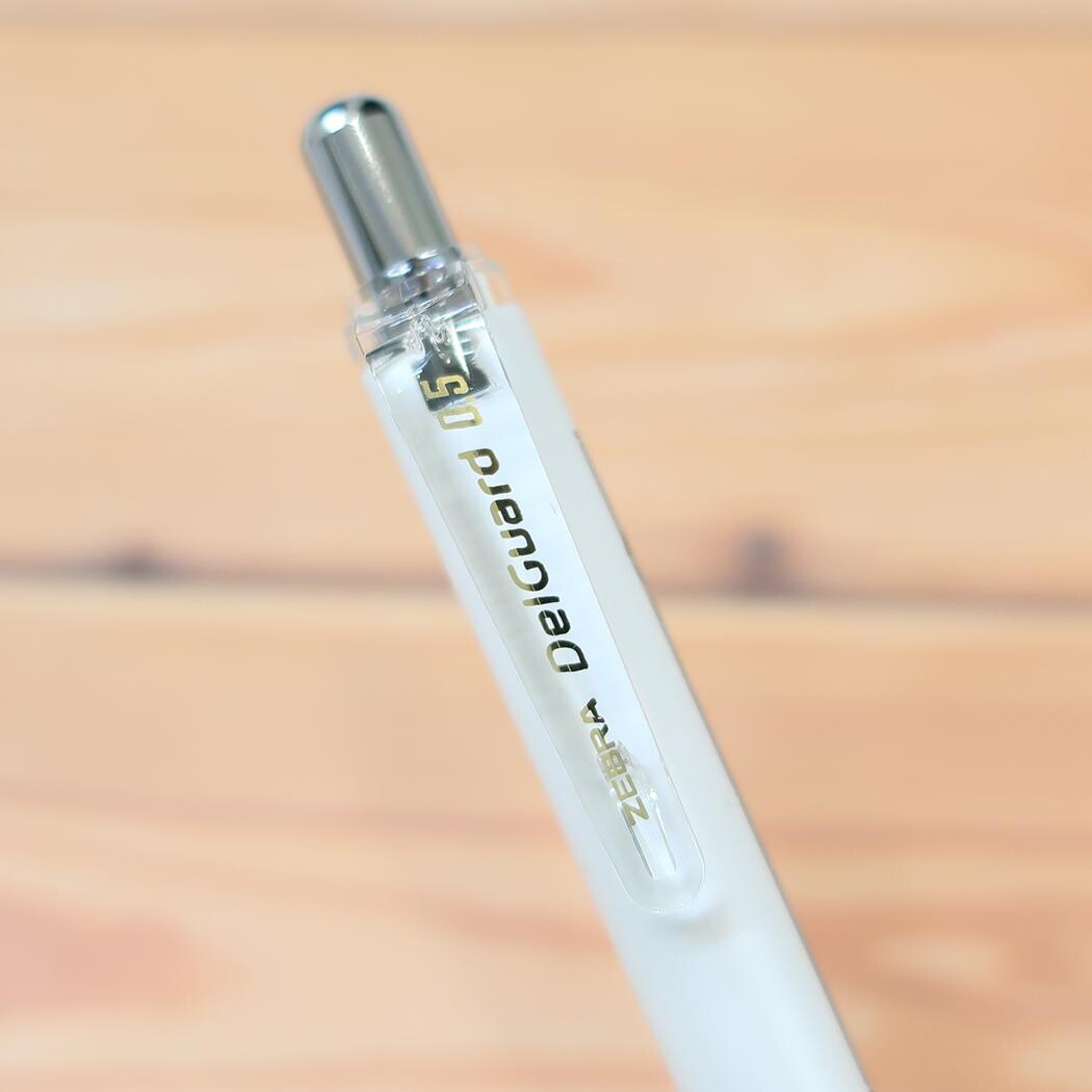 White pencil with silver cap on a wooden surface