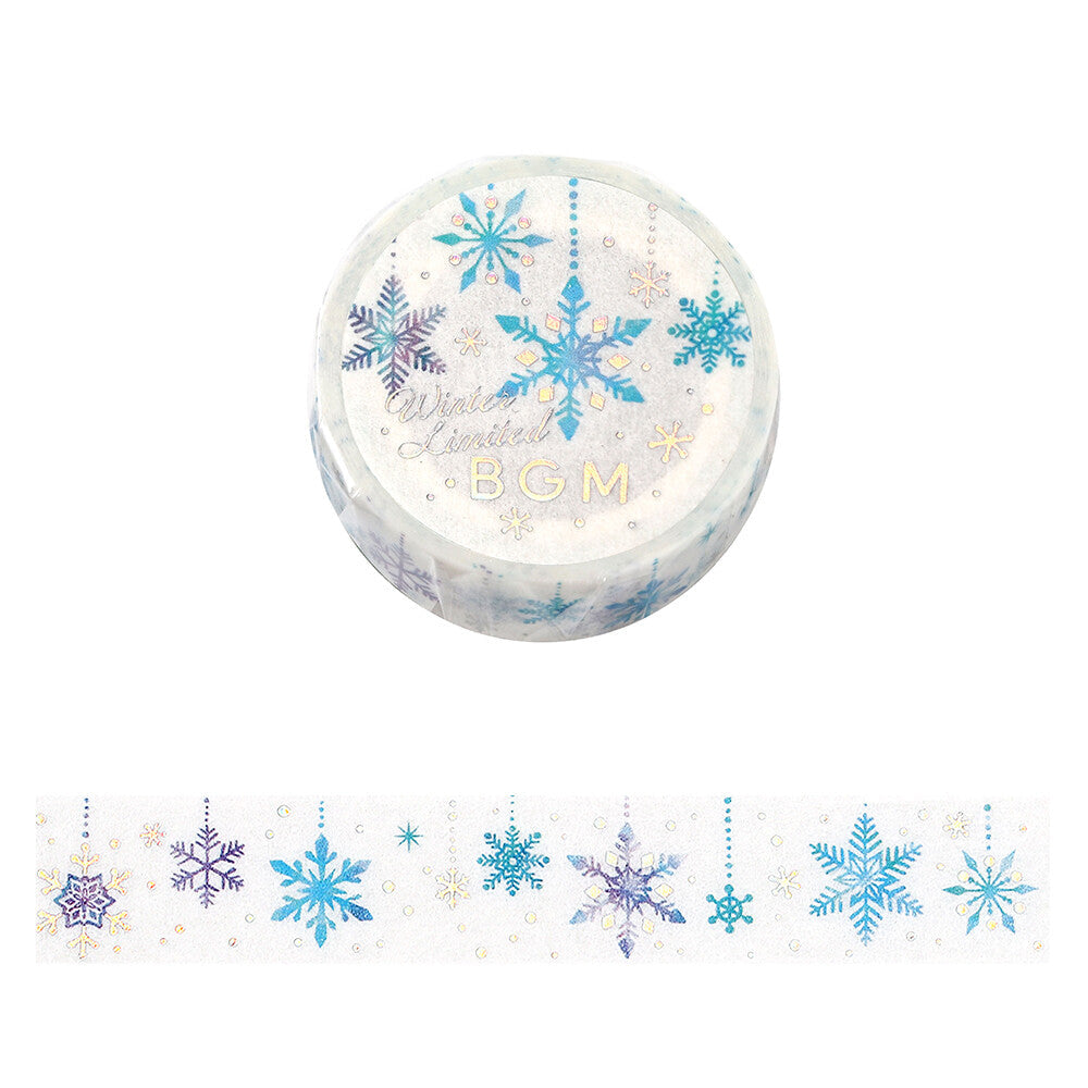 A roll of decorative washi tape with a winter snowflake pattern, shown above a strip of the same tape. The tape features blue, purple, and gold snowflakes on a white background.