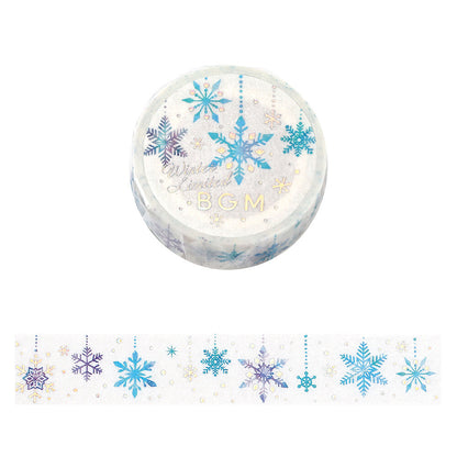 A roll of decorative washi tape with a winter snowflake pattern, shown above a strip of the same tape. The tape features blue, purple, and gold snowflakes on a white background.