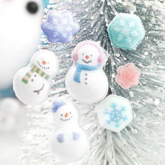 Three white snowman-shaped stickers with colorful scarves and faces, plus three snowflake-shaped stickers in pastel blue, pink, and mint, displayed on a white glittery Christmas tree.