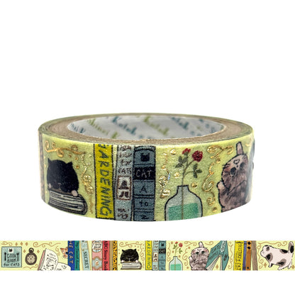 A roll of decorative washi tape featuring cat and book illustrations on a pale yellow background with gold foil accents. 
