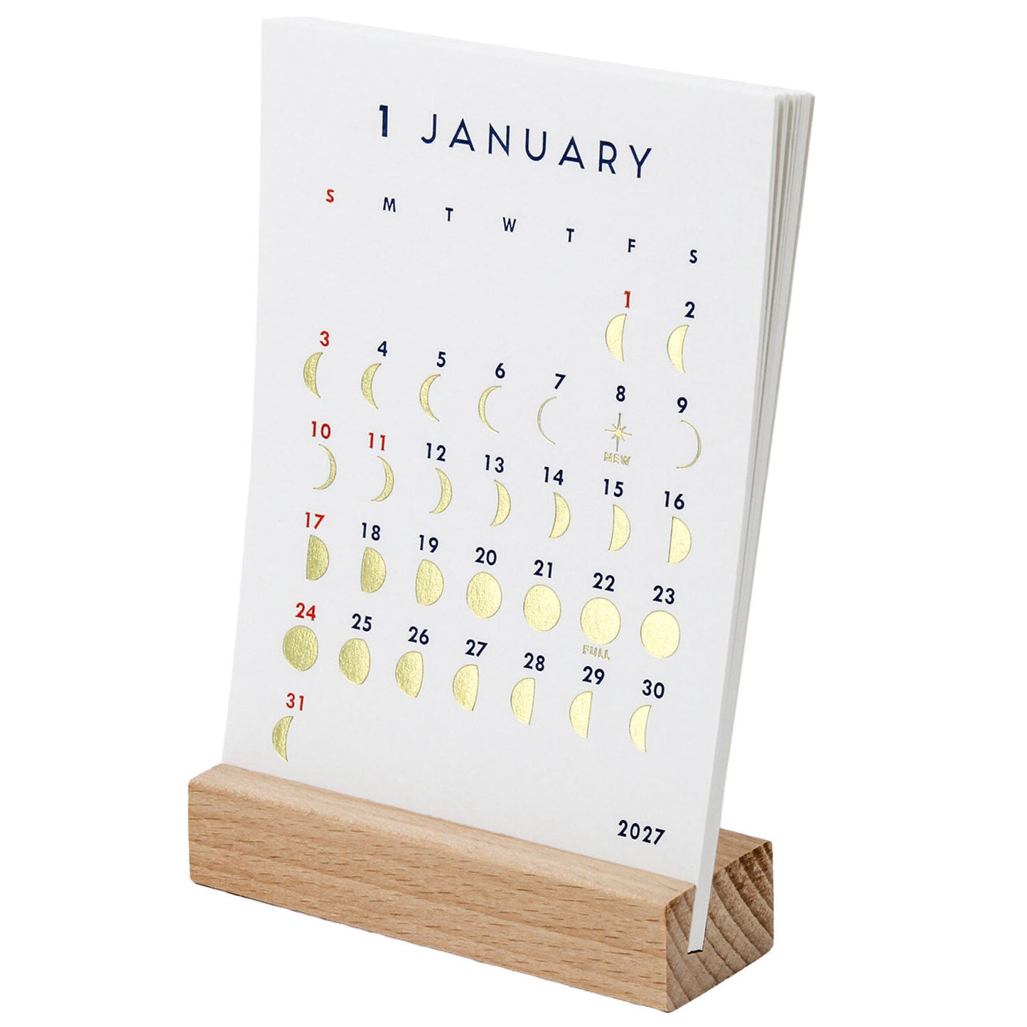 A January 2027 desk calendar with gold foil moon phases and dates, displayed on a light wood block stand against a white background.