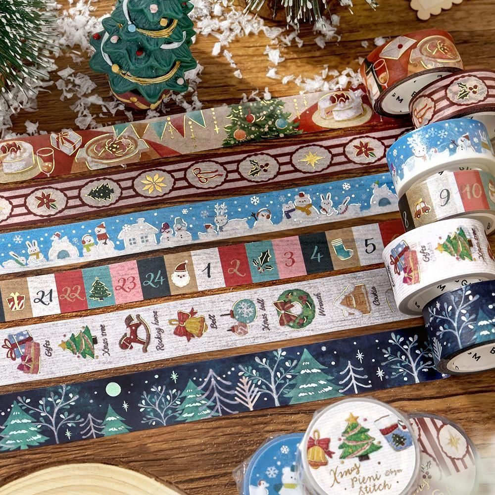 A collection of Christmas-themed washi tapes rolled up and laid out on a wooden surface, featuring festive patterns like snowflakes, Santa Claus, Christmas trees, and holiday numbers.