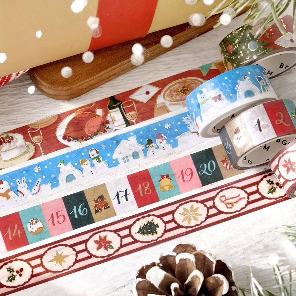 A collection of Christmas-themed washi tapes rolled up and laid out on a wooden surface, featuring festive patterns like holiday feasts, snowmen, Christmas decorations, and holiday numbers.