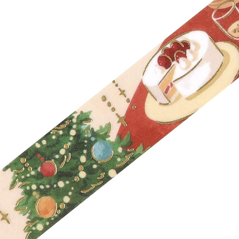 A close-up of washi tape with a Christmas-themed pattern, featuring a green decorated Christmas tree on one side and a slice of cake on a red background on the other, set against a plain white backdrop.