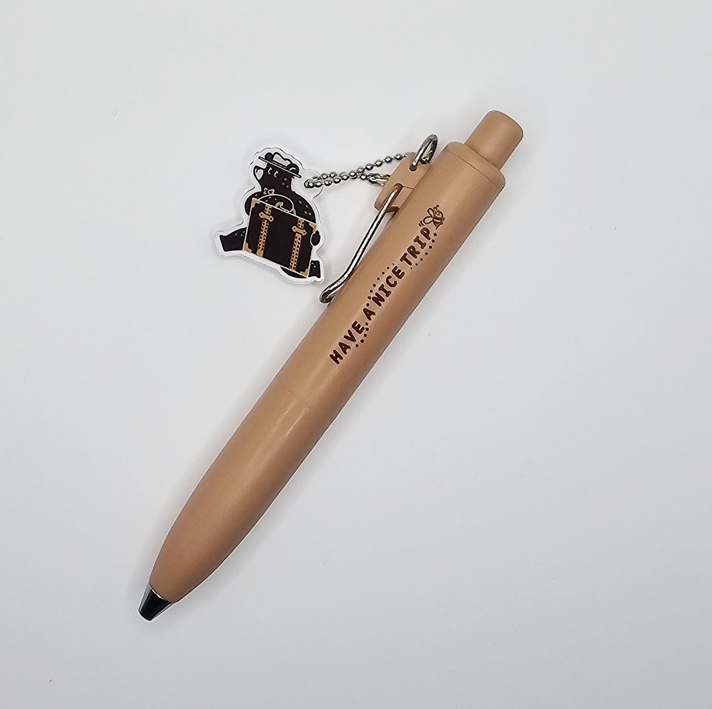 Beige pen with a bear keychain on a white background