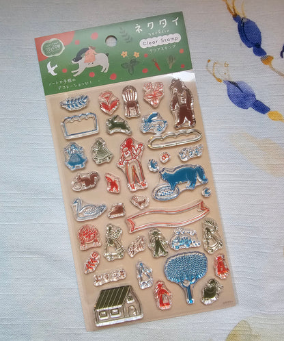 A package of Necktie clear stamps featuring various animal and decorative shapes in red, blue, green, and silver, with a green header card with Japanese text and illustrations, displayed on a patterned fabric background.