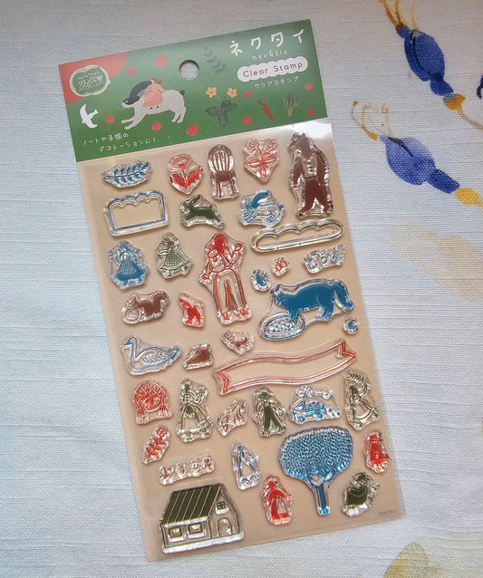 A package of Necktie clear stamps featuring various animal and decorative shapes in red, blue, green, and silver, with a green header card with Japanese text and illustrations, displayed on a patterned fabric background.