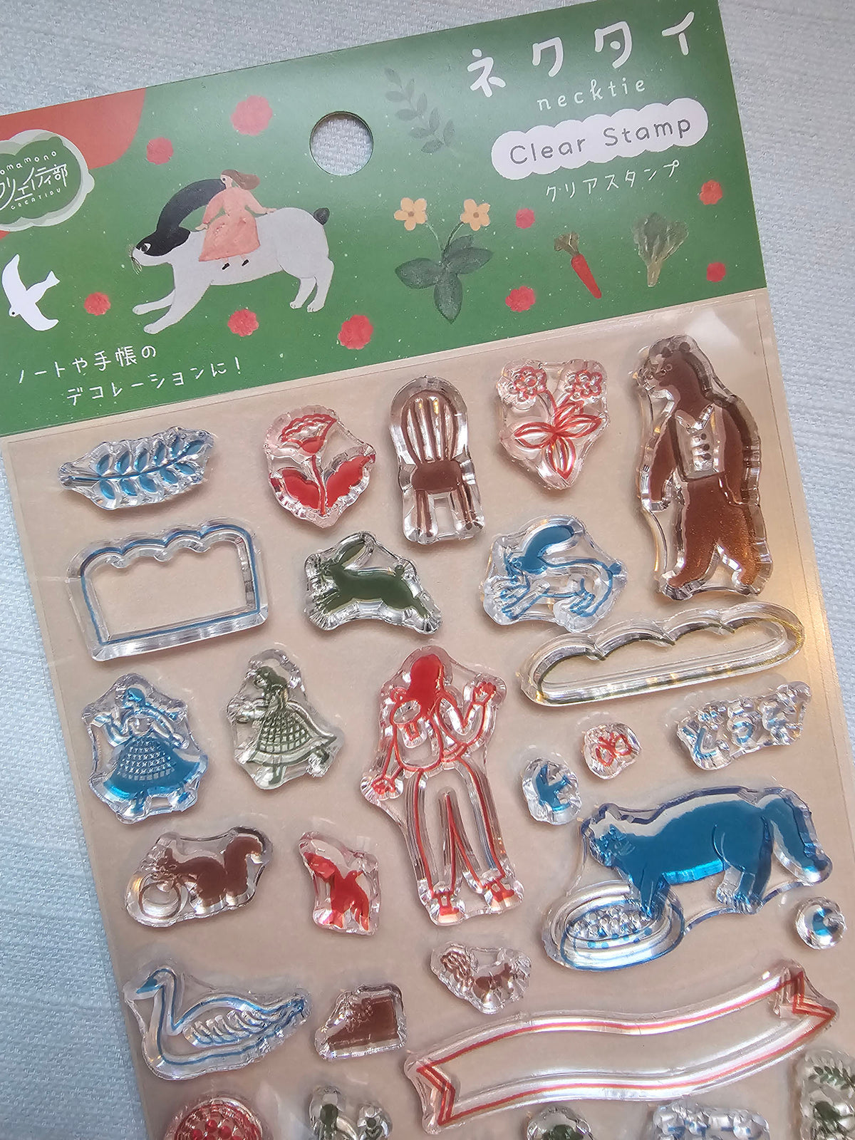A package of Necktie clear stamps featuring various animal and decorative shapes in red, blue, green, and silver, with a green header card displaying Japanese text and illustrations.