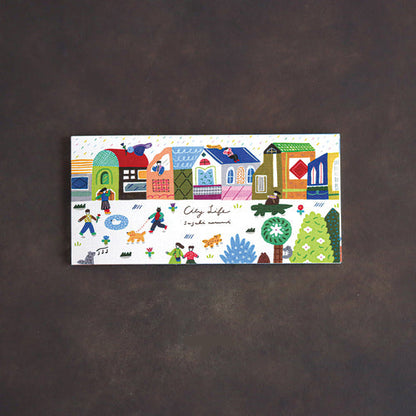 A rectangular notepad featuring a colorful hand-drawn illustration of houses, people, dogs, and trees, with the text 'City life'. Displayed on a dark brown textured background.