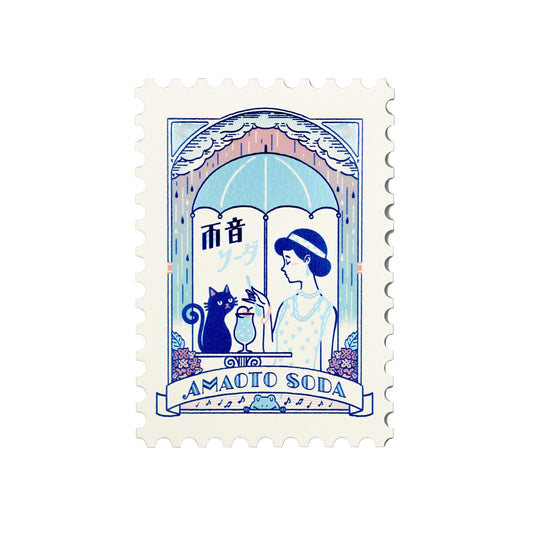 Stylized illustration of a woman, cat, and umbrella with 'AMADO SODA' text on a foil-stamped postcard.