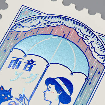 Stylized illustration of a woman, cat, and umbrella with Japanese text on a foil-stamped postcard.