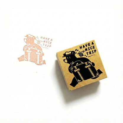 Rubber stamp with 'Have a Nice Trip' text and bear design on a white background