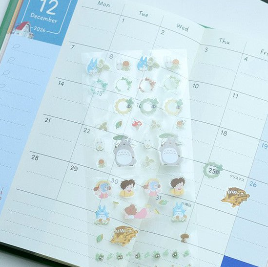A sheet of cute planner stickers featuring Totoro and friends, displayed on an open monthly calendar.