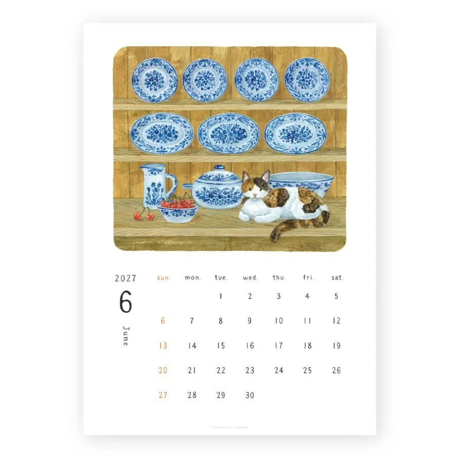 A single-page calendar showing June 2027 on a white page, with a central illustrated panel of blue-and-white ceramic dishes and a calico cat on a wooden shelf.