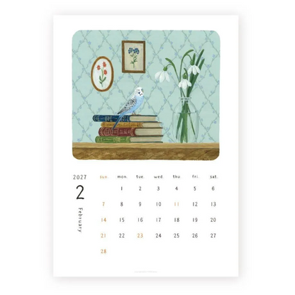 A printed calendar page showing February 2027 with a central illustrated panel of a blue bird on stacked books beside a vase of white snowdrops against a pale blue patterned wall.