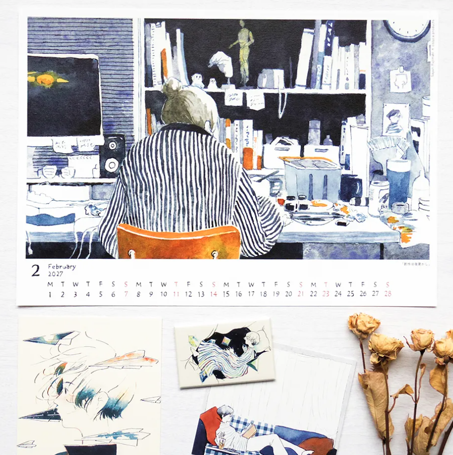 A printed calendar page showing a blue-toned illustration of a person sitting at a desk, with a February 2027 date strip along the bottom. Surrounding the calendar are smaller artwork samples and dried flowers on a light surface.