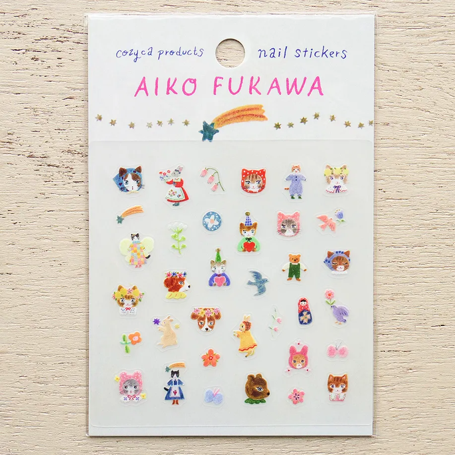 A sheet of Aiko Fukawa nail stickers featuring cute cartoon characters, animals, and flowers on a white backing card, displayed on a light wood background.