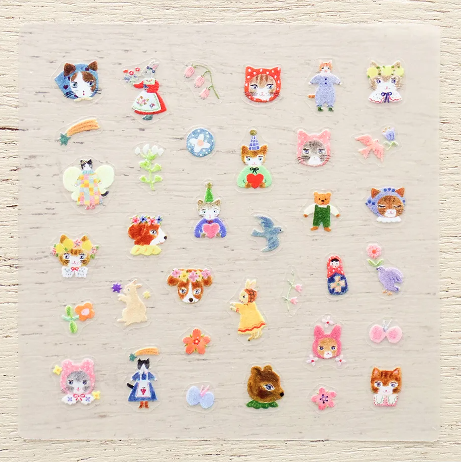 A collection of small, colorful nail stickers featuring various cute characters, animals, and flowers, arranged neatly on a light beige textured fabric background.
