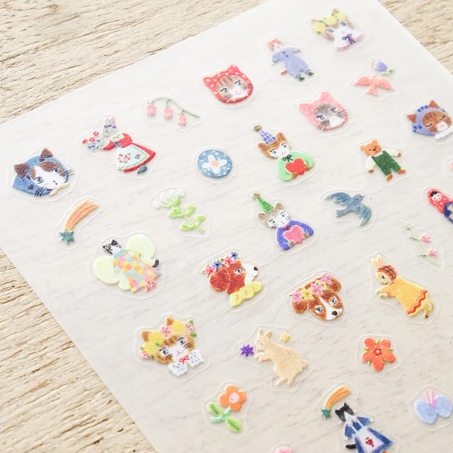 A collection of small, colorful nail stickers featuring various cute characters, animals, and flowers, arranged neatly on a light beige background.