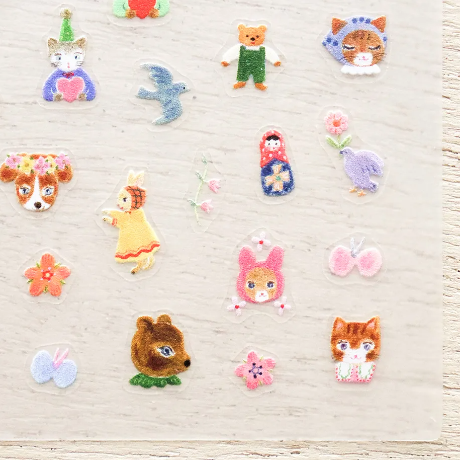 A collection of small, colorful nail stickers featuring cute animal and nature motifs, displayed on a light-colored wooden background.