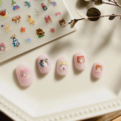 Nail art with cartoon character designs on a light surface with a sheet of stickers in the background.